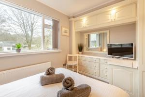 une chambre avec deux serviettes sur un lit avec une télévision dans l'établissement Mews Cottage, à Grasmere