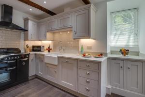 Una cocina con gabinetes blancos y un fregadero. en Memories Cottage, en Milnthorpe