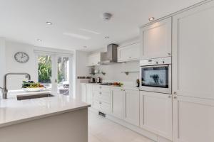 a kitchen with white cabinets and a clock on the wall at Kittiwake Padstow in Padstow