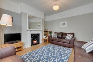 a living room with a couch and a tv and a fireplace at Kittiwake Padstow in Padstow