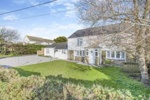an exterior view of a white house with a yard at Elmwood Cottage in St Merryn