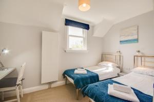 1 dormitorio con 2 camas, lavabo y ventana en Allseasons, en Fowey