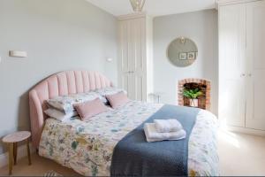 a bedroom with a pink bed with towels on it at Honey Cottage in Richmond