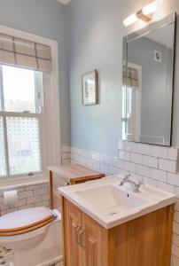 a bathroom with a sink and a toilet and a mirror at Honey Cottage in Richmond