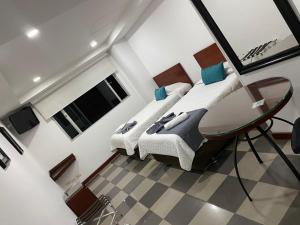 1 dormitorio con 2 camas y mesa de cristal en MV Hotel Kafir, en Bogotá