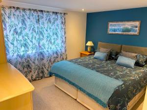 a bedroom with a bed with a blue wall at Valley View in Mevagissey