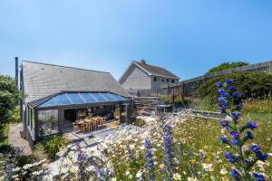 a garden with blue flowers and a house at Pen Y Mor in Mawgan Porth