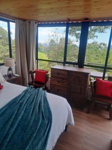 a bedroom with a bed and a dresser and windows at Alojamiento natural rural LOS NOGALES in San Francisco