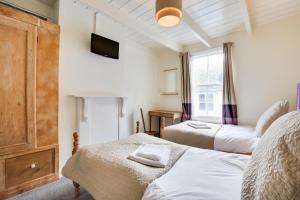 Un dormitorio con dos camas y un televisor en la pared. en 6 Baileys Lane, en St Ives