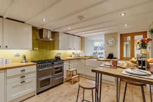 a kitchen with white cabinets and a table with chairs at High Green Cottage in Low Eskcleth