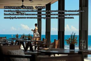 a woman walking in a restaurant with a view of the ocean at InterContinental Sanya Resort by IHG in Sanya