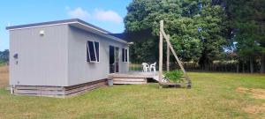 a tiny house with a porch and a swing at Houhora Hideaway in Houhora