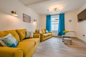 sala de estar con sofá amarillo y cortinas azules en Summer Breeze - St Ives, en St Ives