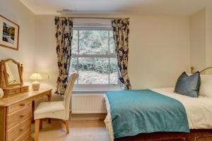 Un dormitorio con una cama y un escritorio y una ventana. en Summerville, en Lynmouth
