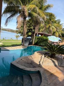 a swimming pool with a bench and palm trees at Pontal do Lago Flat in Caldas Novas