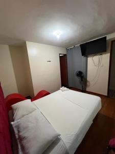 a bedroom with a white bed and a television at Hostal Las Vegas in Lima