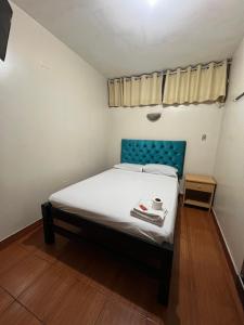 a small bedroom with a bed with a blue headboard at Hostal Las Vegas in Lima