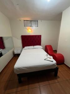 a bedroom with a bed and a red chair at Hostal Las Vegas in Lima