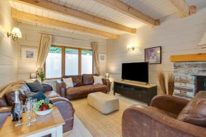 a living room with leather furniture and a flat screen tv at Honeywood in Little Petherick