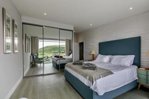 a bedroom with a large bed with a blue headboard at Shore End - W1 in Woolacombe +23 photos
