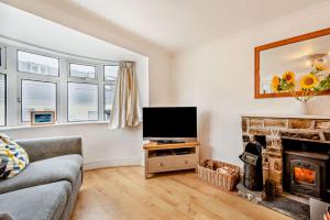 un soggiorno con tv e camino di Hillcrest Cottage a Little Haven