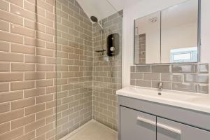 un bagno con lavandino e doccia con specchio di Hillcrest Cottage a Little Haven Altre 20 foto