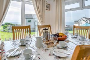 a dining table with a white tablecloth and a bowl of fruit at Heavenly View in Southerndown