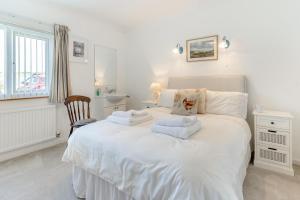 a bedroom with a white bed with towels on it at Heavenly View in Southerndown