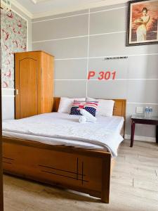 ein Bett mit einem Holzrahmen in einem Zimmer in der Unterkunft Mini hotel Trịnh Huỳnh in Phan Thiet