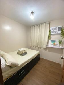 a small bedroom with a bed with white sheets at Spacious Condo Staycation in Pasig City in Manila