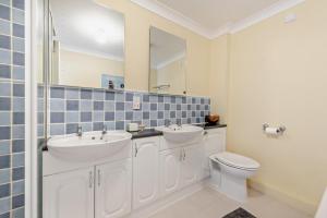 a bathroom with two sinks and a toilet and a mirror at Broadview in Broad Haven +12 photos