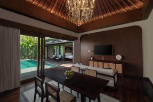 Una sala de estar con una mesa de comedor y un televisor. en The Garcia Ubud Villa, en Ubud
