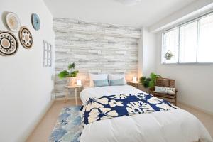 a bedroom with a large bed with blue and white sheets at アロハベース in Takamatsu
