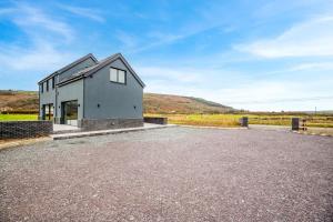 a house on the side of a gravel lot at Siop Penrallt- Rhiw in Bottwnog