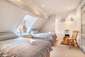 a attic bedroom with two beds and a chair at Stone House in Alcester