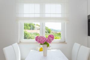 une table blanche avec un vase et des fleurs violettes sur lui dans l'établissement Apartment & Room Ladisic, à Orašac