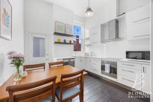 a white kitchen with a wooden table and chairs at The Alto in Ballarat