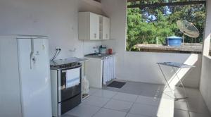 a white kitchen with a sink and a stove at Recanto verde pousada in Angra dos Reis