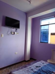 a bedroom with purple walls and a tv on the wall at Hospedaje in Aguaytía +4 photos