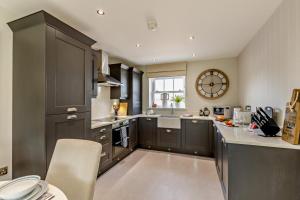 een keuken met zwarte kasten en een klok aan de muur bij Charter Gardens Cottage in Kirkby Stephen +11 foto's