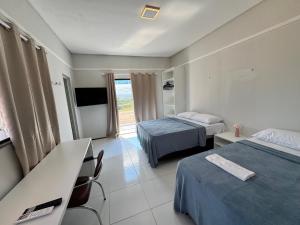 a hotel room with two beds and a television at Pousada do Horto in Juazeiro do Norte