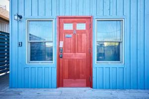 a red door and two windows on a blue building at TOOD一宮-A棟 in Ichinomiya