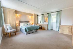Un dormitorio con una cama y una silla y ventanas. en Trenoweth Sea View, en Saint Keverne