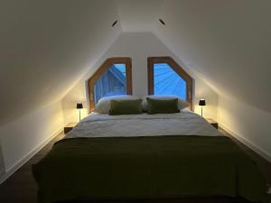 a bedroom with a large bed with two windows at 4 Elements Glamping & Apartments in Bled