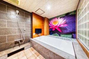 a bathroom with a tub and a painting of a flower at Hotel Lotus Mito-Adult Only in Mito