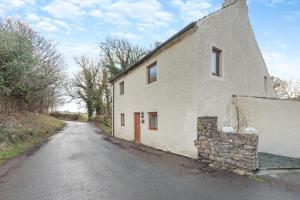 an old white building on the side of a road at Isel Gate Cottage in Sunderland