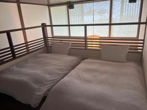 two beds sitting in a room with windows at 大同ガーデンホテル湯の山リゾート in Wada +14 photos