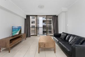 a living room with a black leather couch and a table at Fiori Apartments in Sydney