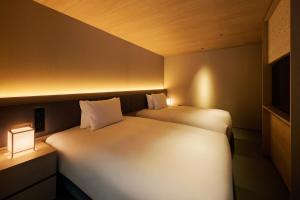 two beds in a small room with a light at ふふ東京銀座 in Tokyo