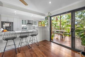 Una cocina con tres taburetes de bar y una cocina con patio. en Tranquil Hideaway in Redcliffe, en Redcliffe
